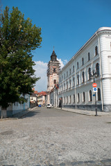 Cobbled square in the Old town. Church building with scaffolding for reconstruction in the distance in the street on blue sky background