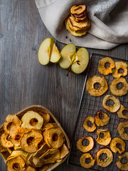 Tasty apple chips on wooden table in wicker basket, with kitchen linen towel, copy space