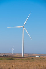 	Huge wind generators against blue sky. Group of spinning wind turbines in wheat field on blue sky background