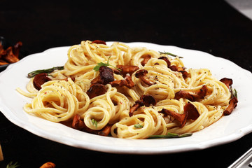 pasta with organic chanterelles. portion of spaghetti pasta with fried chanterelles in a creamy garlic sauce with cheese on a table