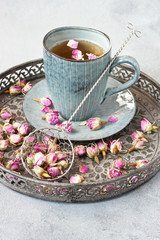Composition with dried rose buds of  tea and vintage sieve  on tray