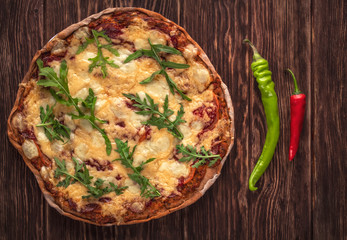 Homemade pizza on the outside background. Top view. Near the pizza are two chili peppers.