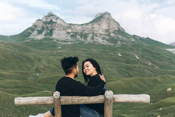 Young couple together on a wooden bench on a background of a mountain landscape in Montenegro.