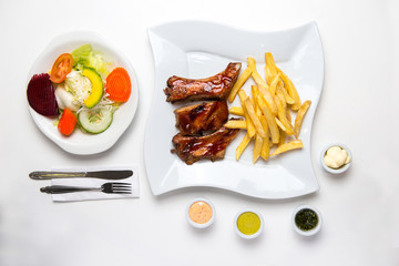 Barbecue ribs with french fries, salad and cream. BBQ. Top view.