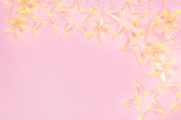 Composition light garland a on pink background. Frame of garland star on pink background. Festive concept,xmas background.Flat lay, top view and copy space