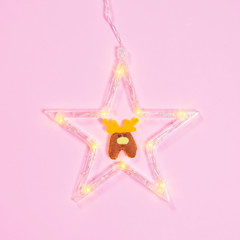 Glowing star with a deer on a pink background. Minimal flat lay Christmas theme. New year sale concept.