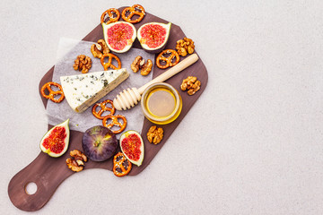 Cheese platter (board) with blue cheese, honey, walnuts, figs, pretzels