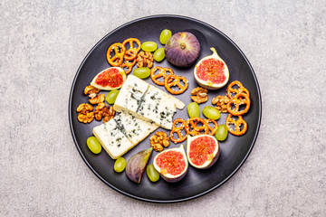 Cheese plate with blue cheese, walnuts, figs, grapes, pretzels