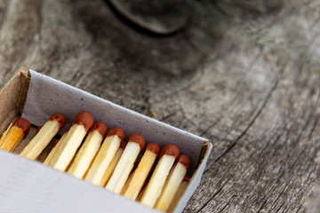 Wooden match in box on a wooden background. Fire safety concept, fire and tree. Close-up shot. Matches in an open matchbox on a dark wooden base.