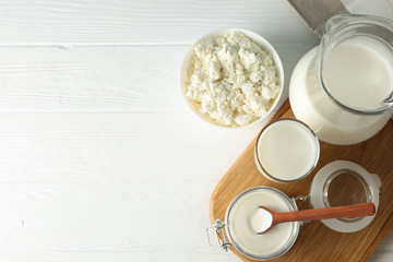 Flat lay. Fresh dairy products, board and towel on white wooden table