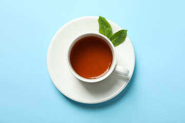 Cup of tea and mint leaves on blue background, copy space