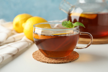 Cup of tea, mint, lemon, tea pot and towel on white background, copy space