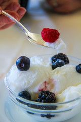 macro shot of lemon ice cream cup with blackberries and raspberries and a teaspoon that is picking up a little