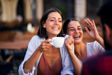Laughing young friends drinking coffee