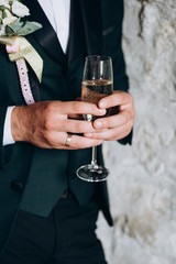 Close up of groom holds a glass of champagne. Party and holiday celebration concept