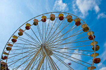 A colourful ferris wheel carousel at a fun fair by daylight in the sun