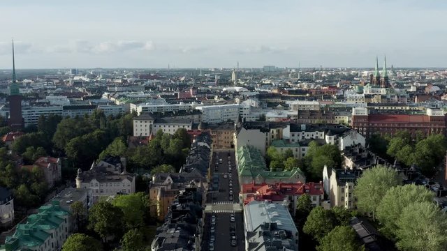 Aerial, reverse, drone shot, over the Eira cityscape, overlooking streets and buildings, the st john and the mikael agricola church, on a sunny, summer day, in Helsinki, Uusimaa, Finland
