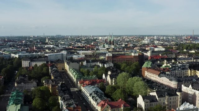 Aerial, reverse, drone shot, over the Eira cityscape, overlooking buildings and the st john church, on a sunny, summer day, in Helsinki, Uusimaa, Finland
