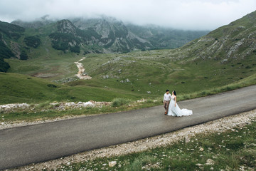 The bride and groom are on the road in the highlands. Wedding in the mountains.