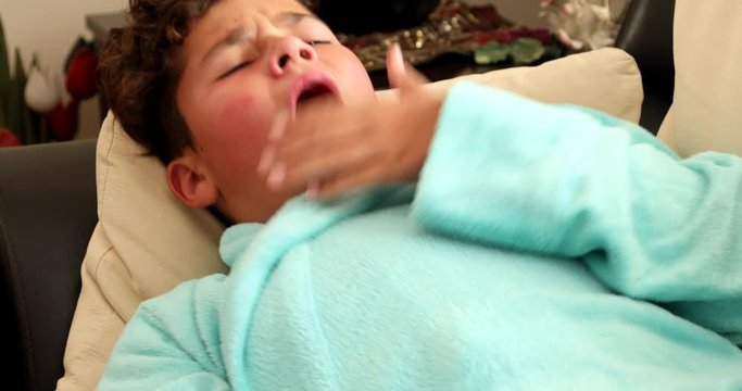 Tired, weak young boy at home sick with flu lying on sofa  and resting