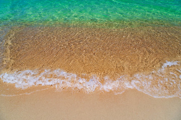 Ocean turquoise, yellow sand, waves, sunlight.