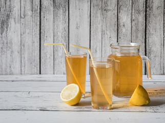 Kombucha fungus. Organic fermented tea drink with lemon on a white wooden table.