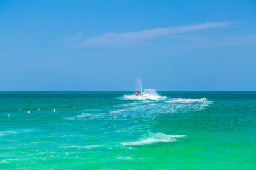 The ocean is turquoise and the boat water bike is far away with two people. Thailand. Samui. Gulf of Thailand. Lamai Beach