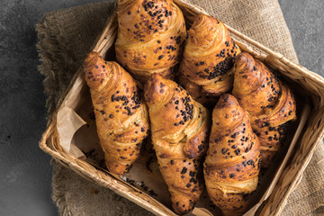 Tasty and fresh french croissants in a wicker basket close up on a grey table as background