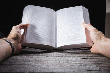 Young male reading an empty open book on a desk - insert your own message