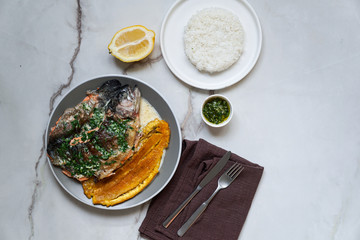 Colombian and Mexican, Venezuela food - trucha al ajillo -  river trout, served with a large,fried plantain, patacon and garlic sauce