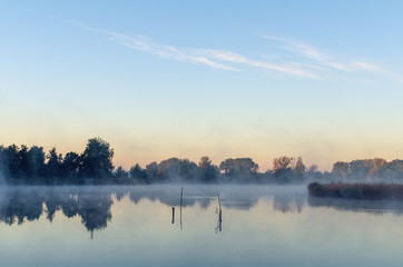Naklejka na ściany i meble Morning landscape with fog over the lake