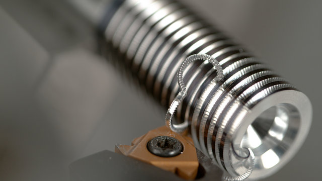 MACRO: CNC Machine Slowly Threading A Small Metal Workpiece Into A Shiny Screw