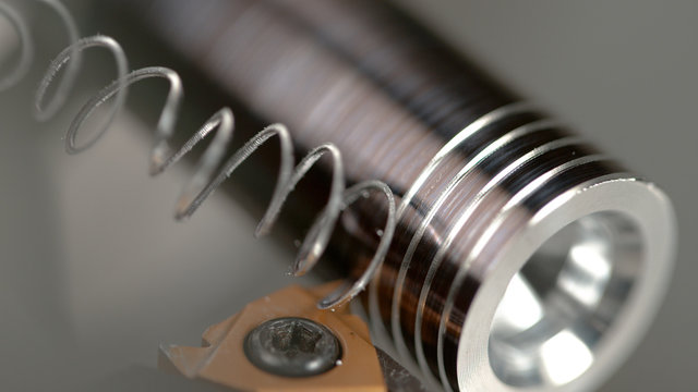 MACRO, DOF: Sharp cutter carves a thread into a small metal rod during threading