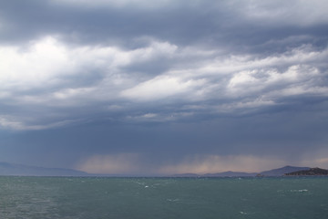 Heavy, storm clouds over the ocean, herald the arrival of a storm. Beautifully illuminated dark clouds and reflections in the ocean water