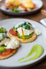 Pancakes with poached egg, tomato, avocado and sauteed spinach. Close up view.