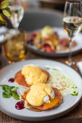 Pancakes with poached egg and smoked salmon. Served table for breakfast.