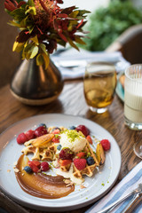 Golden waffle topped with vanilla ice cream, caramel sauce, fresh fruit and berries. Breakfast in restaurant