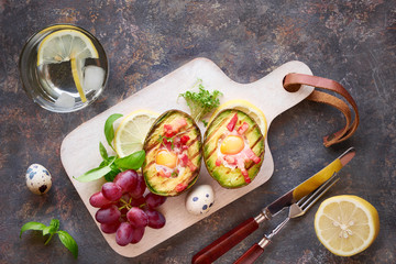 Top view on grilled avocado boats with bacon and quail eggs