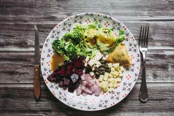 Assiette de salade composée avec dés de fromage betteraves échalotes graines de courge samoussa	