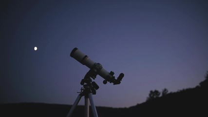Silhouette of a telescope with evening sky in the background.