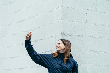 a young woman with sport clothes making a selfie with a white background