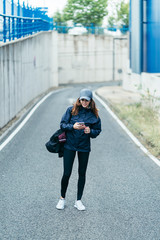 a young woman walking along the road with an smartphone with sport wear © Mikel Taboada