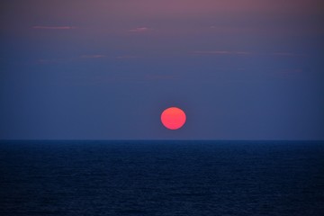 a sunrise at the seashore in red and blue colors