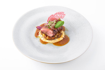 Tender pork in a sauce with caramelized vegetables and artichoke puree. Banquet festive dishes. Fine dining restaurant menu. White background.