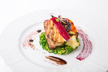 Tender grilled pork meat, vegetables and berry sauce. Banquet festive dishes. Gourmet restaurant menu. White background.