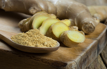Fresh chopped ginger root and ground ginger powder in wooden spoon on wooden rustic table. Healthy food spice concept. Zingiber officinale