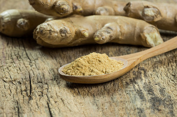 Fresh ginger root and ground ginger powder in wooden spoon on wooden rustic table. Healthy food spice concept. Zingiber officinaleiber officinale