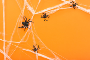 Halloween background with spider web and spiders as symbols of Halloween on the orange background. Happy Halloween concept. Frame. Copy space.