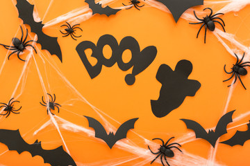 Halloween decorations with spider, web, ghost and spiders as symbols of Halloween on the orange background. Happy Halloween concept.