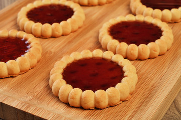 Raspberry jam tarts on wooden board 